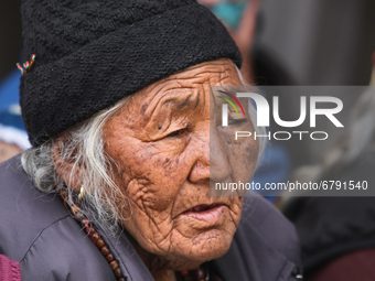 Elderly Ladakhi woman watches as Buddhist monks perform ancient sacred dances during the Lamayuru Masked Dance Festival in Lamayuru, Ladakh,...