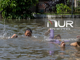 South Tangerang, Banten, Indonesia, 12 June 2021 :Children playing in the middle of the ongoing flood.  Floods that hit Nerada Estate housin...