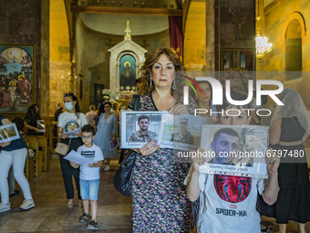 Relatives of killed soldiers in the last Nagorno Karabakh conflict with Azerbaijan, show  their photos during a holy mass in a church of Yer...