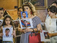 Relatives of killed soldiers in the last Nagorno Karabakh conflict with Azerbaijan, show  their images during a holy mass in Yerevan, Armeni...