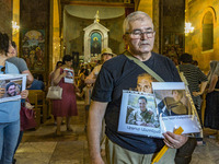 A man holds photos of his relatives, killed soldiers in the last Nagorno Karabakh conflict with Azerbaijan, during a holy mass in a church o...