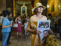 A woman holds photos of his relatives, soldiers killed in the last Nagorno Karabakh conflict with Azerbaijan, during a holy mass in Yerevan,...