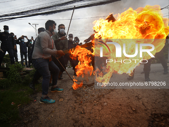Police personnel attempt to douse an effigy of Nepal’s Prime Minister KP Sharma Oli burnt by the opposition alliance during a Protest agains...