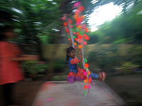 A slum living girl enjoying in a decorated swing on the occasion of Rajo festival in the eastern Indian state Odisha's capital city Bhubanes...