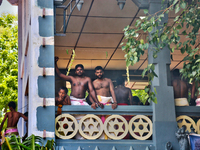 Tamil Hindus watch as devotees perform the para-kavadi ritual (where they are suspended by hooks driven into their back and legs and bounced...