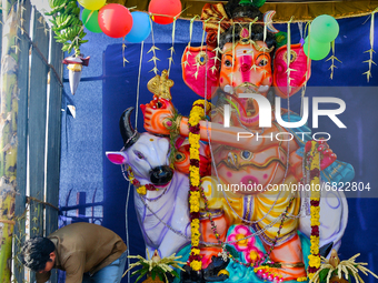 Man does final the decorating touches at a shrine with a large idol of Lord Ganesha (Lord Ganesh) along the roadside during the festival of...