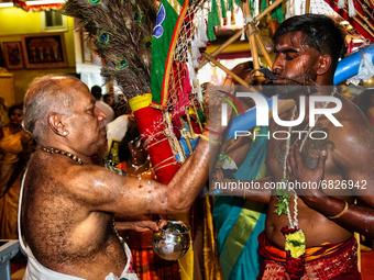 Tamil Hindu priest splashes water on the face of a Hindu devotee before blessing him after the devotee completed the Kavadi Attam ritual (a...