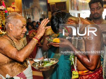 Tamil Hindu devotee receives blessings from a Hindu priest after performing the Kavadi Attam ritual (a ritual where he is pulled while danci...
