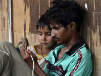 A homeless child and a man watches a smartphone screen in Kolkata, India, 24 June, 2021. Mobile phone production down 50% amid Coronavirus s...