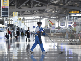 A cleaning worker wearing protective masks cleans at the Suvarnabhumi International Airport amid a new wave of the coronavirus disease (COVI...