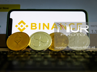 Binance logo displayed on a phone screen and representation of cryptocurrencies are seen in this illustration photo taken in Krakow, Poland...