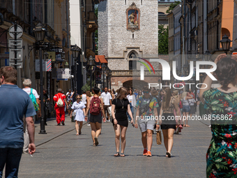 People in their summer outfit walk at Florianska Street in the old town of Krakow as another heat wave approaches Poland and central Europe...