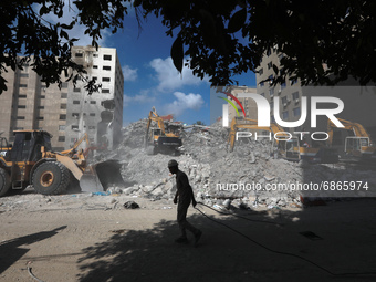 Egyptian workers and machines clear the remaining rubble of Al-Jalaa tower, a building that was levelled in an Israeli attack during the 11-...