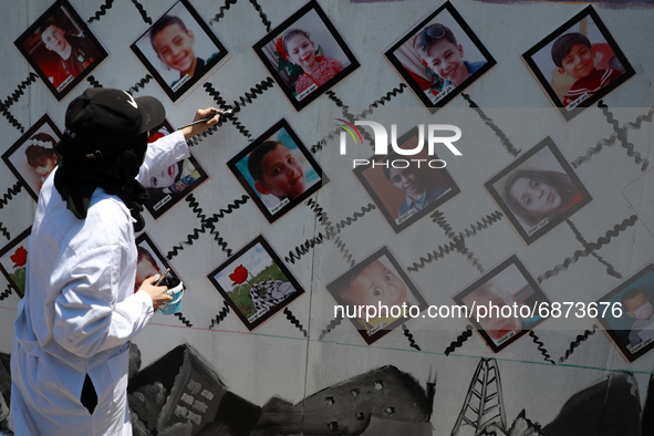Palestinian artists take part in an event as they draw murals and hang pictures of children who killed during the recent Israeli military es...