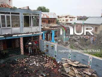 Kashmiri people assess the damaged residential house where three militants were killed in a military operation in Newa area of Pulwama distr...