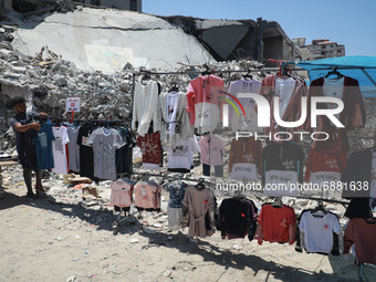 A Palestinian street vendor sells clothes near the rubble of al-Shuruq tower in Gaza City's al-Rimal neighbourhood which was targeted by Isr...