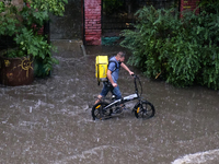 Food courier on a flooded street during a heavy downpour in Kyiv, Ukraine. July 19, 2021  (