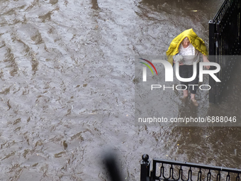 A woman walks down a flooded street during a heavy downpour in Kyiv, Ukraine. July 19, 2021  (