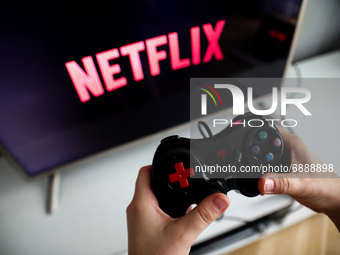Netflix logo displayed on a tv screen and a gamepad are seen this illustration photo taken in Krakow, Poland on July 19, 2021. (