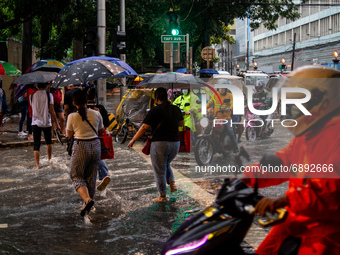People wade through a flooded street following heavy rains in Manila,  Philippines, on July 21, 2021.(