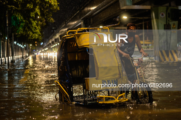 A pedicab driver wades through a flooded street following heavy rains in Manila,  Philippines, on July 21, 2021.