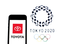 In this photo illustration a Toyota Motor Corporation logo seen displayed on a smartphone with a Tokyo 2020 Olympic Games logo in the backgr...