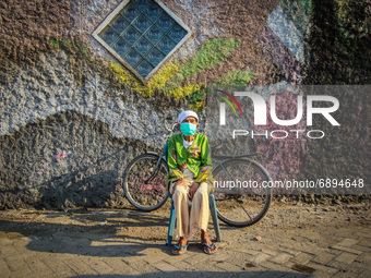 An old woman sunbathing in a fishing village in Tambaklorok, Semarang, Central Java Province, Indonesia on July 21, 2021. (