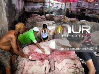 Workers applying salt on raw cattle skin for preservation at Posta area in Dhaka, Bangladesh on July 22, 2021.  (