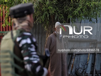 A kashmiri man watches as Security forces are seen near Encounter site in Warpora, Sopore District Baramulla, Jammu And Kashmir, India on 23...