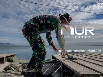 A Indonesian Army soldier pick up plastic waste scattered in the Talise Beach area, Palu, Central Sulawesi Province, Indonesia on July 23, 2...