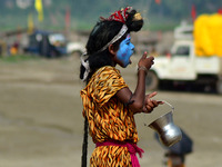 An indian boy dressed as hindu God Shiva,eats prasad which devotees give after taking a holy dip at sangam,cofluence of River Ganga,yamuna a...