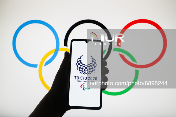Tokyo 2020 Paralympic Games logo is displayed on a mobile phone screen photographed with Olympic Rings symbol background for illustration ph...