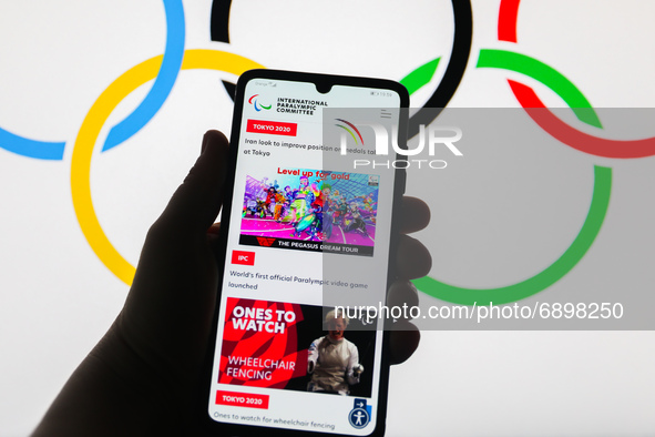 Tokyo 2020 Paralympic Games official website is displayed on a mobile phone screen photographed with Olympic Rings symbol background for ill...