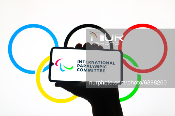 International Paralympic Committee logo is displayed on a mobile phone screen photographed with Olympic Rings symbol background for illustra...