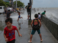 Children play in floodwater near the shore of the polluted Manila Bay in Tondo district, Manila City, Philippines on July 26, 2021. Typhoon...