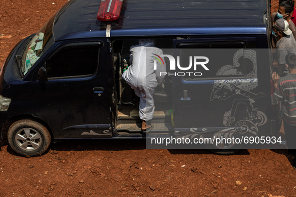 An ambulance officer using PPE pushed the coffin from the car to be taken to the burial site, in Banten, South Tangerang, Indonesia, on July...
