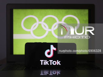 TikTok logo is displayed on a mobile phone screen photographed with Olympic rings symbol on the background for illustration photo. Leszczewe...