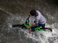 A boy ride bicycle on  waterlogged street during rain in Jaipur, Rajasthan, India, on July 26, 2021. (