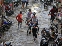 Commuters wade through a waterlogged street during rain in Jaipur, Rajasthan, India, on July 26, 2021. (