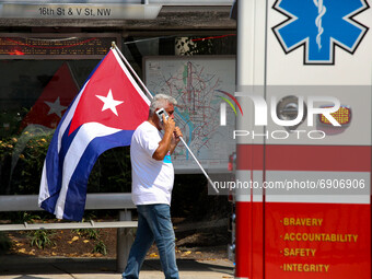 A demonstrator holding a Cuban flag talks on his phone as an ambulance passes during a demonstration opposing Cuba's government in Washingto...