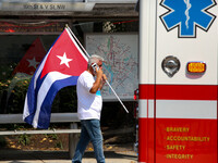 A demonstrator holding a Cuban flag talks on his phone as an ambulance passes during a demonstration opposing Cuba's government in Washingto...