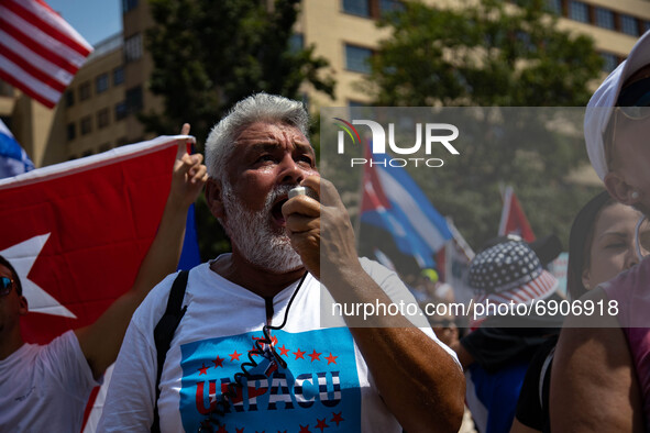 A man yells into a megaphone as thousands of demonstrators opposing Cuba's government gather outside of the Cuban Embassy in Washington, D.C...