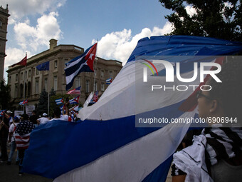 A woman waves a flag as thousands of demonstrators opposing Cuba's government gather outside of the Cuban Embassy in Washington, D.C. after...