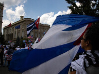 A woman waves a flag as thousands of demonstrators opposing Cuba's government gather outside of the Cuban Embassy in Washington, D.C. after...