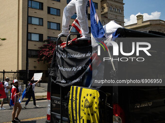 A man stands on top of a vehicle as thousands of demonstrators march from the White House to the Cuban Embassy in Washington, D.C. on July 2...