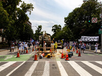 Construction workers watch as thousands of demonstrators march from the White House to the Cuban Embassy in Washington, D.C. on July 26, 202...