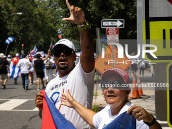 A demonstrator displays a 'L' hand gesture during a march from the White House to the Cuban Embassy in Washington, D.C. on July 26, 2021 (