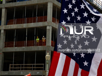 Construction workers watch from the top of a building as thousands of demonstrators march from the White House to the Cuban Embassy in Washi...