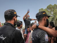 A supporter of Kais Saied sits on an other’s shoulders as he chants slogans against the islamist party Ennahdha in front of the riot police,...