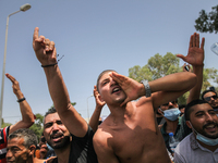 Supporters of Kais Saied chant slogans against the islamist party Ennahdha as they lift fist, during a demonstration held in front of the bu...